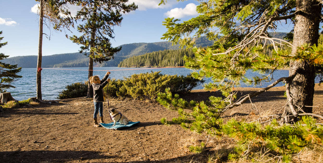 A woman puts a collapsible water bottle in her dog's Ruffwear Palisades Pack. 