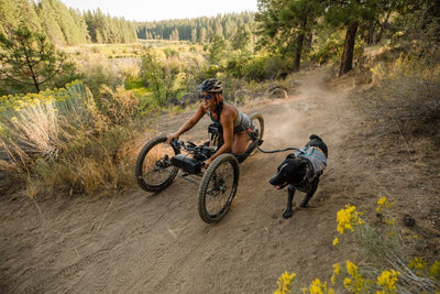 Anna on off road handcycle and Bernie on leash next to her bike down the River Trail in Bend.