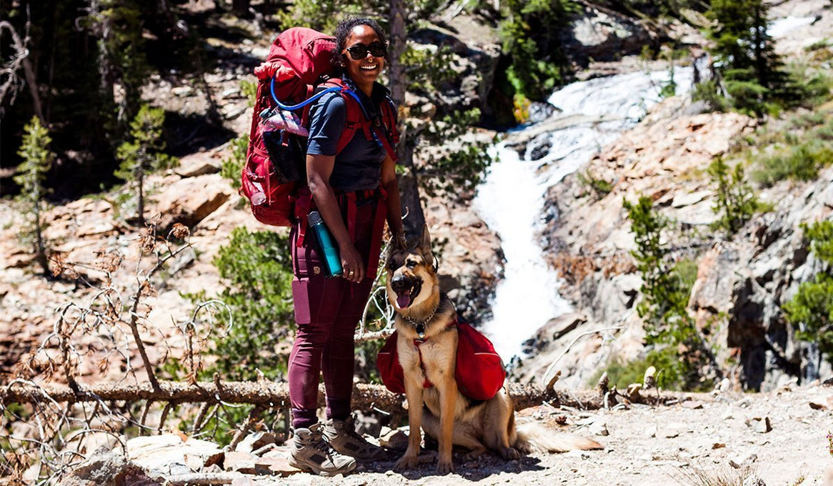 Noami and Amara in backpacks by a waterfall.
