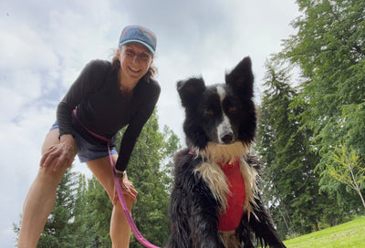 A woman and her dog smile at the camera on a break from running. 