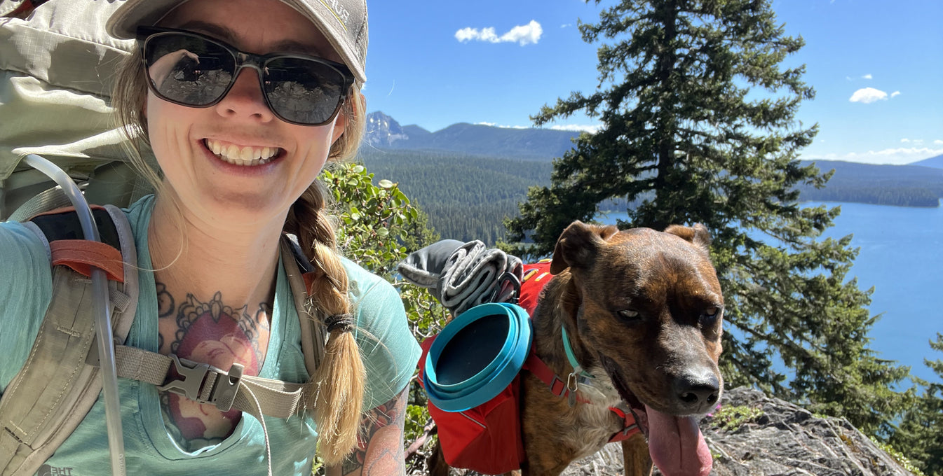 A woman goes backpacking in the mountains with her dog. 