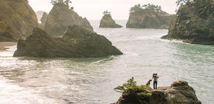 Trevor and Kahlua on point looking out over crazy rock formations in the water on Oregon Coast.