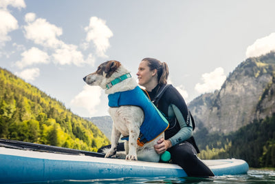 Woman sitting on a paddleboard with her dog.