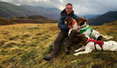 Ambassador Kerry with his three dogs in ruffwear harnesses outdoors.