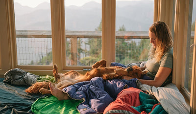 Bailey lays on her back across Elise's lap inside a fire lookout.