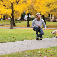 A man skateboards with his small dog