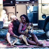 Noami and Dustin sit with Amara on rug outside van.